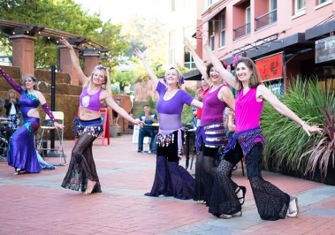 Students of bellydance teacher Dhyanis perform in black and purple costumes at San Rafael farmers market.